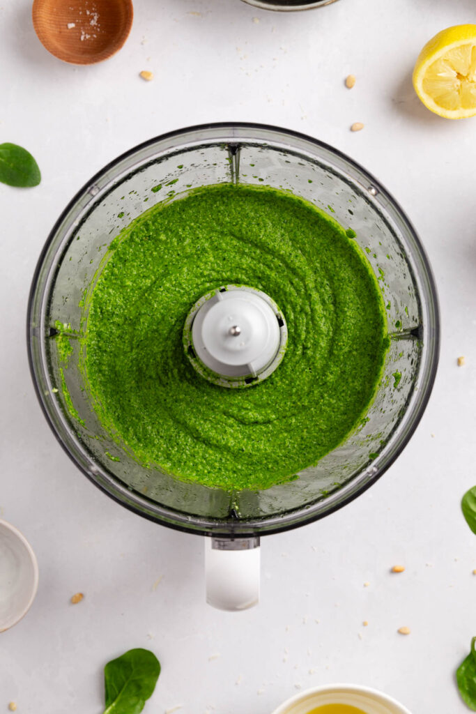 Overhead photo of food processor bowl with smooth spinach pesto