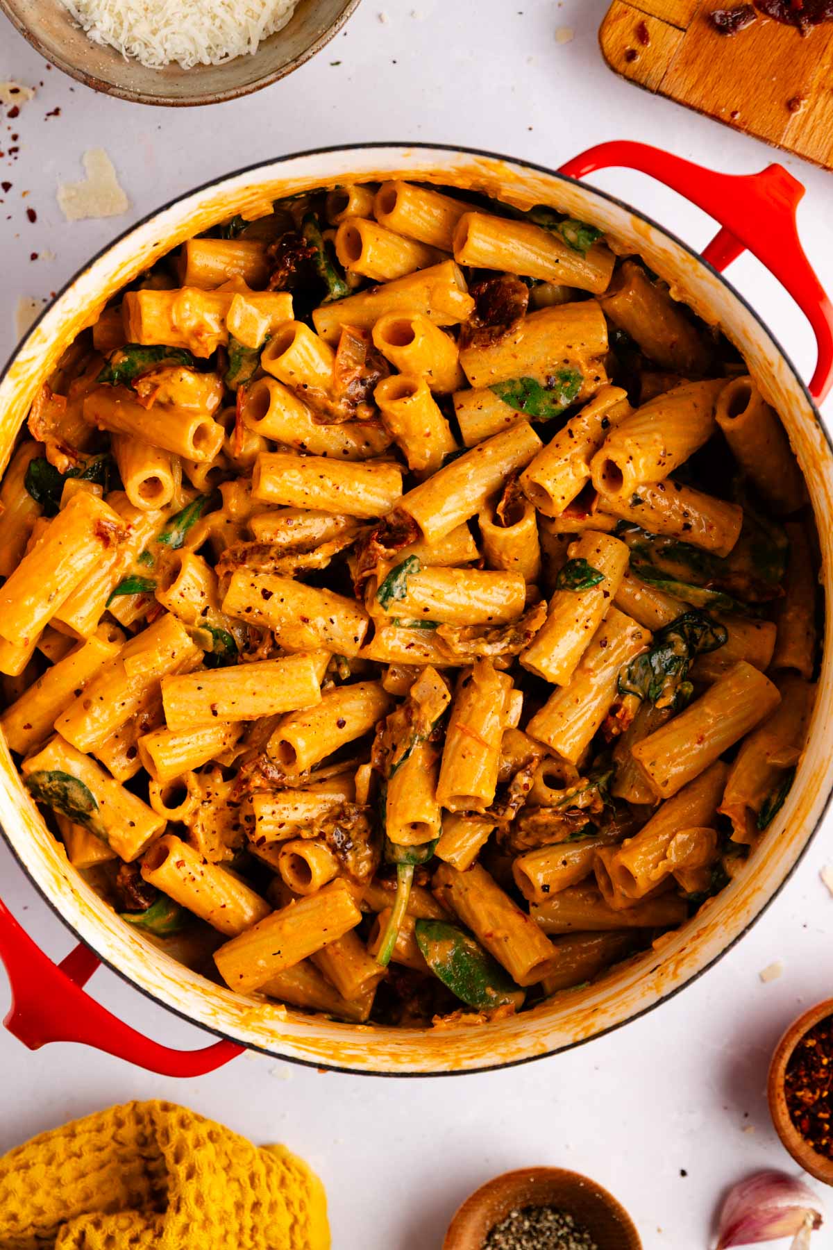 Overhead view of creamy vegetarian Marry Me Pasta in a large sauté pan, showing rigatoni coated in creamy tomato sauce with spinach and sun-dried tomatoes.