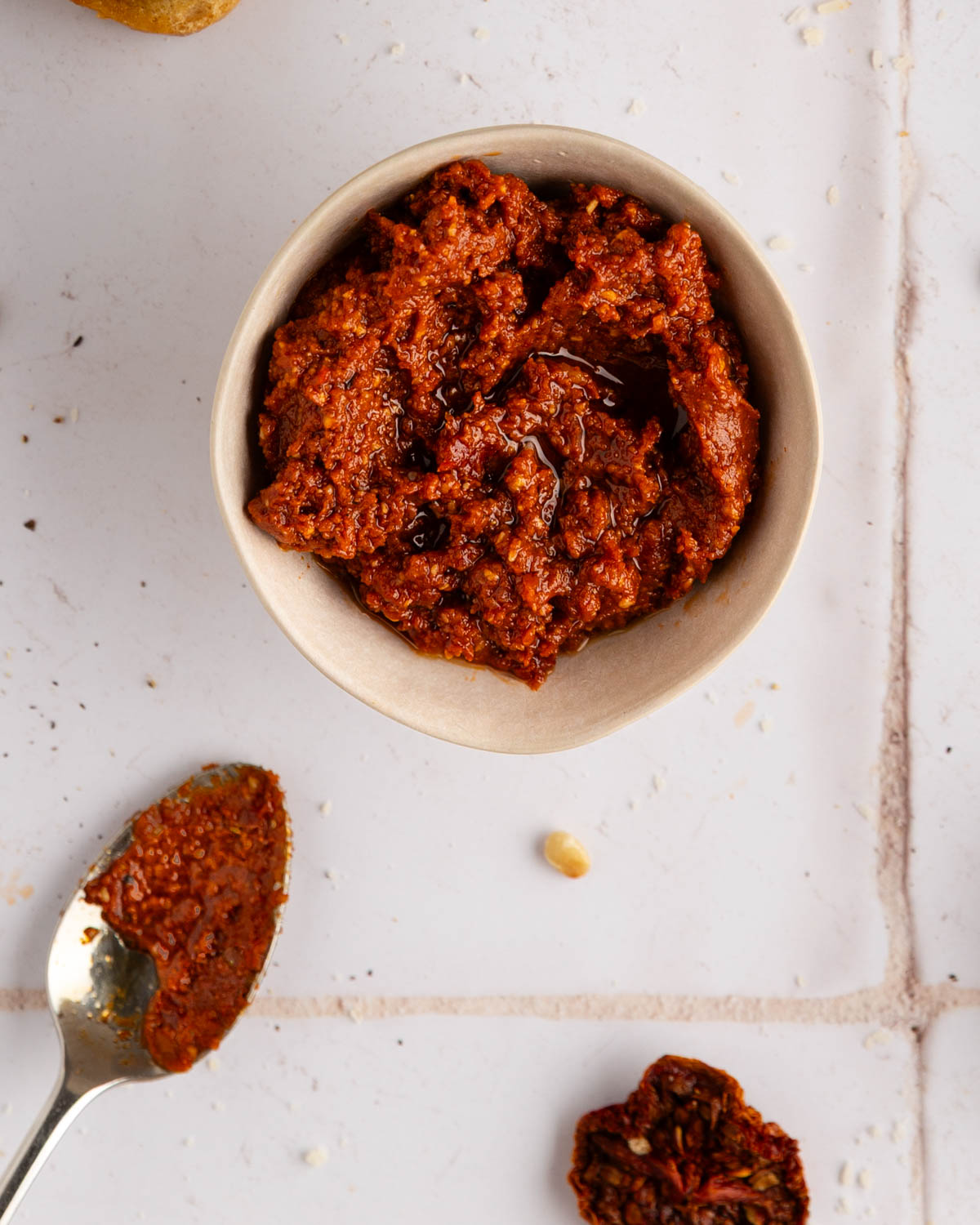 bowl of smooth sun dried tomato pesto with a spoon for dipping or serving