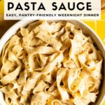 White bowl of creamy chickpea pasta sauce tossed with fettuccine on a yellow tile background