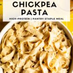 Overhead view of a white bowl of creamy chickpea fettuccine on a yellow tile background