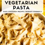 White skillet filled with wide pasta noodles in a silky chickpea pasta sauce on a bright yellow tile surface