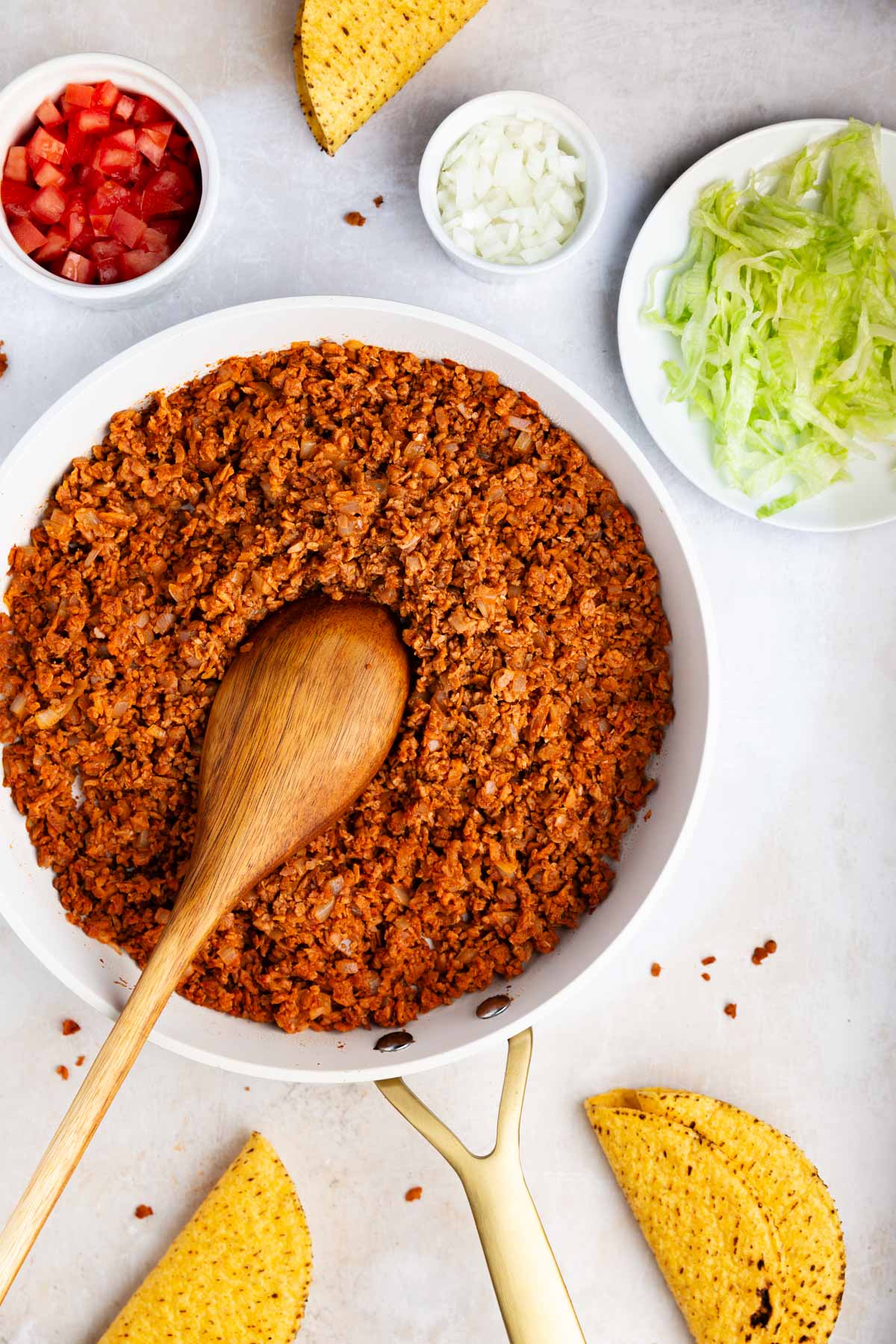 textured vegetable protein taco meat in a white bowl with a wooden spoon