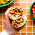 Cheesy Pinto Bean Burritos cut in half with a hand holding it to show the filling