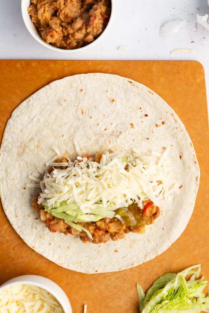 adding the bean mixture into the flour tortillas