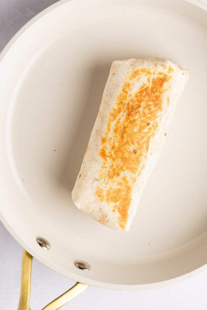 putting the rolled burrito into the skillet to brown