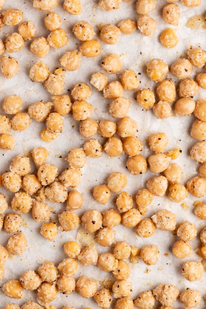 Coated chickpeas in a single layer on a baking sheet.
