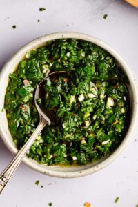 Garlic parsley sauce in a white bowl with a spoon.