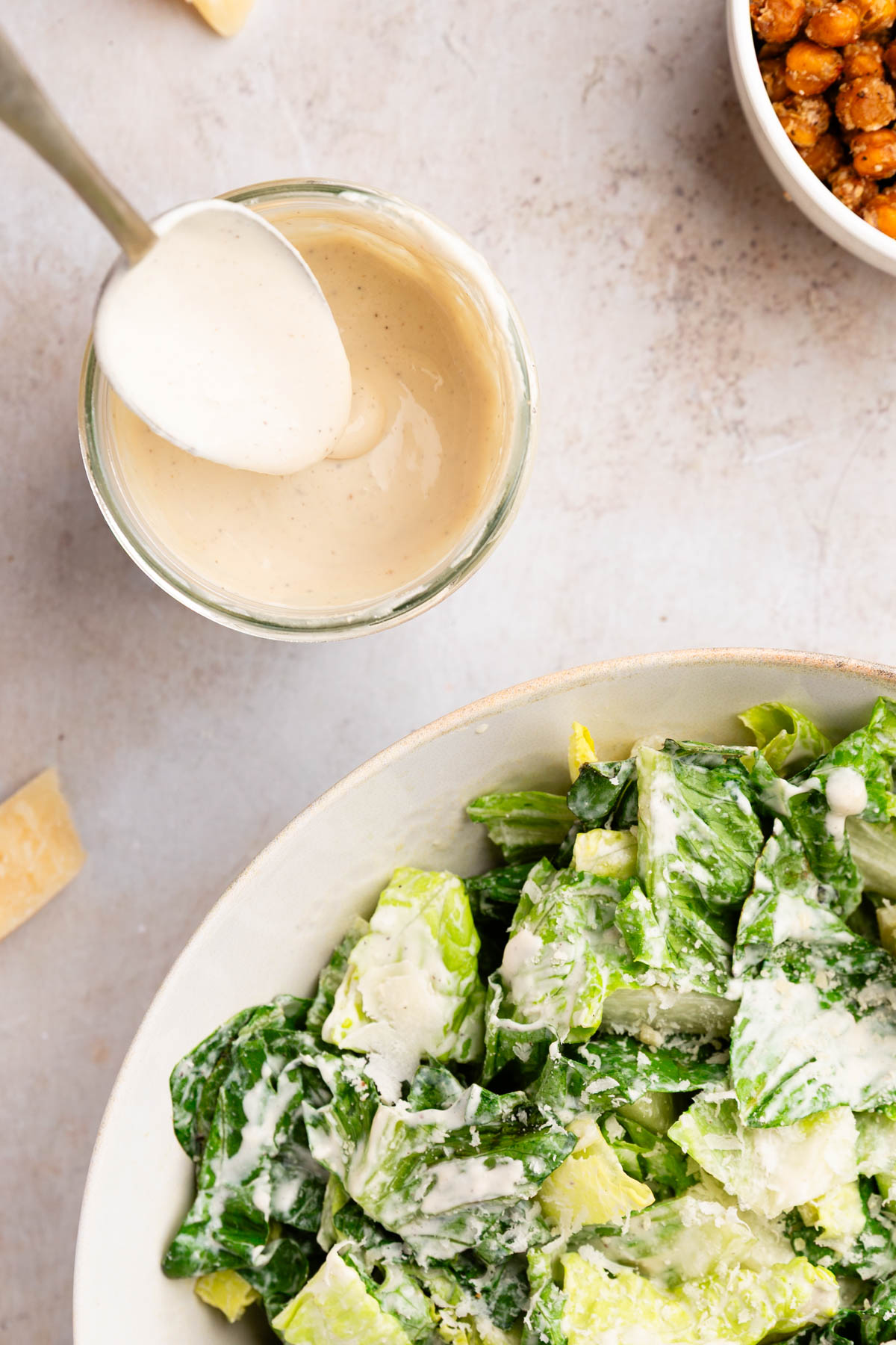 overhead photo of a spoon pulling out of a glass jar of healthy caesar dressing made with cottage cheese 