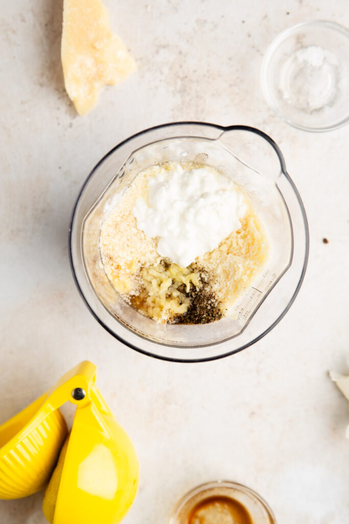 ingredients for a healthy caesar dressing made with cottage cheese in a mixing container
