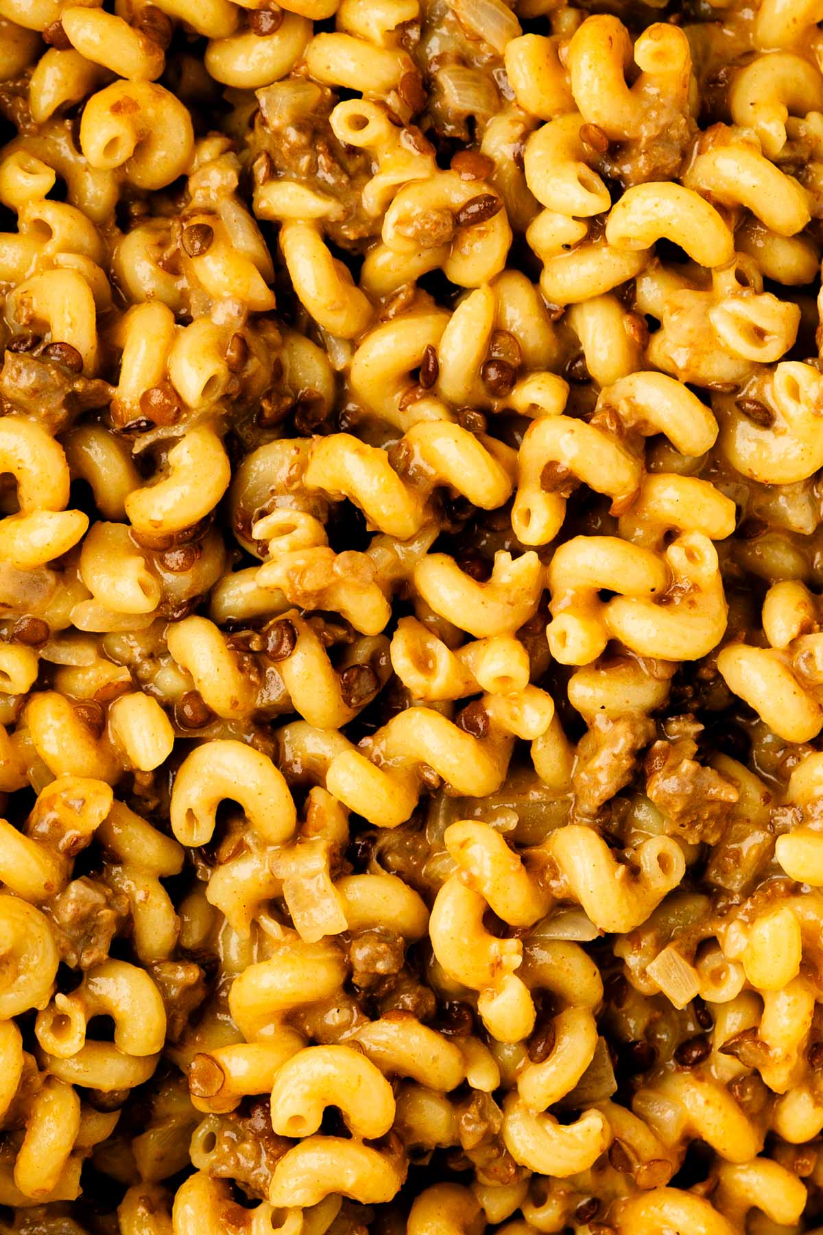 Close-up of cheesy one-pot Hamburger Helper with cavatappi, ground beef, lentils, and diced onion.