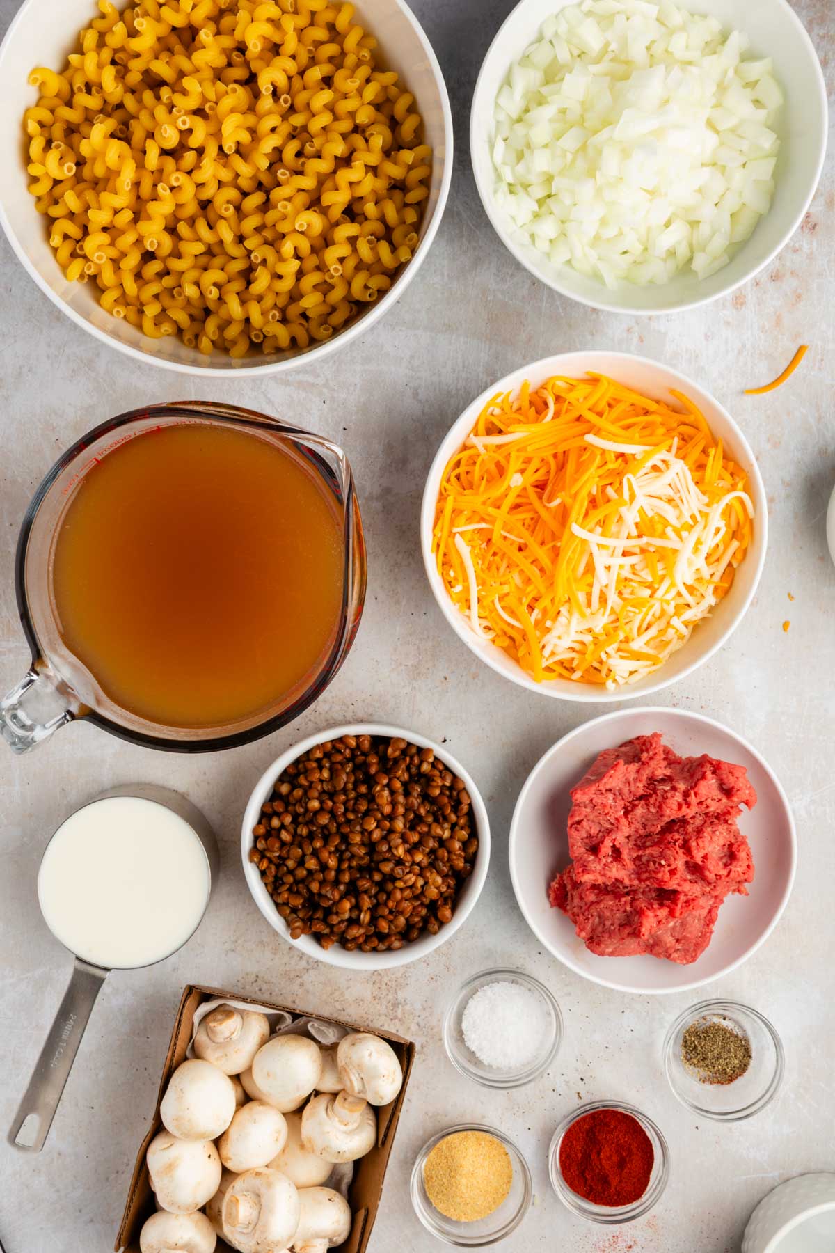 Ingredients for healthier cheeseburger pasta, including cavatappi, ground beef, lentils, mushrooms, cheese, and broth.