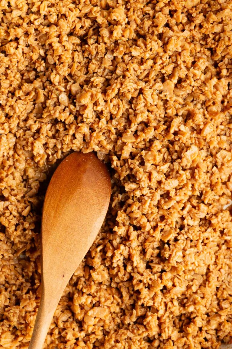 Close-up of cooked vegan ground meat and a wooden spoon, showing its crumbly, ground-beef-like texture.