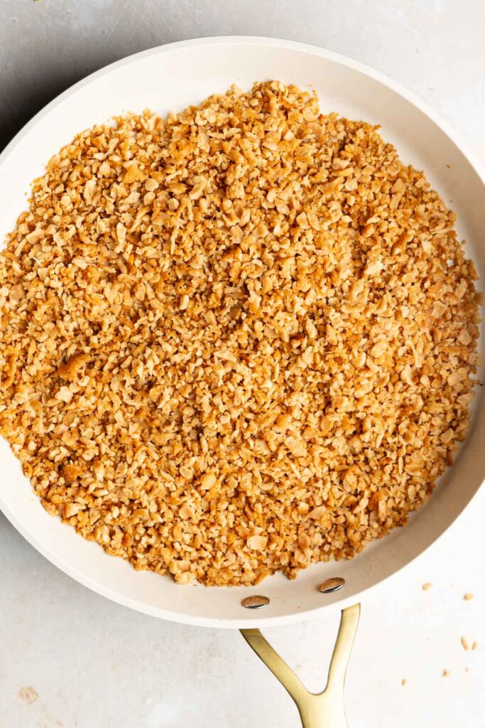 Golden, lightly crisp TVP granules browning in a white skillet.